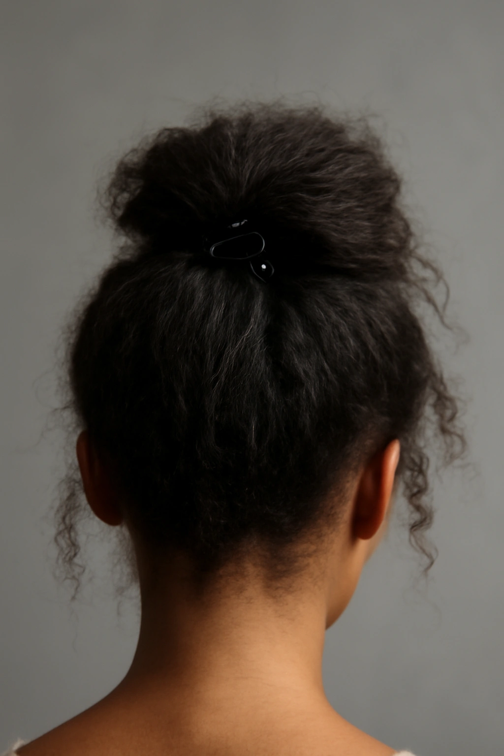 Close-up of a tousled high ponytail secured with a claw clip, emphasizing crown lift and texture
