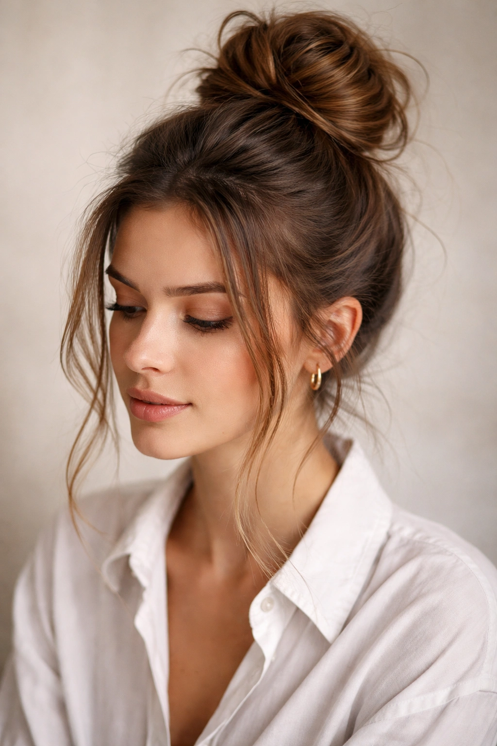 Close-up of a textured, messy high bun with face-framing strands.