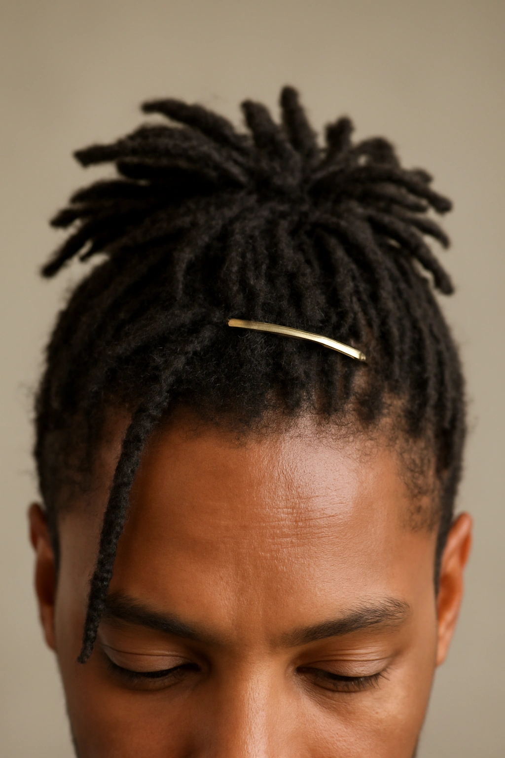 Short dreadlocks styled with a minimalist clip shaping the crown for a polished look.